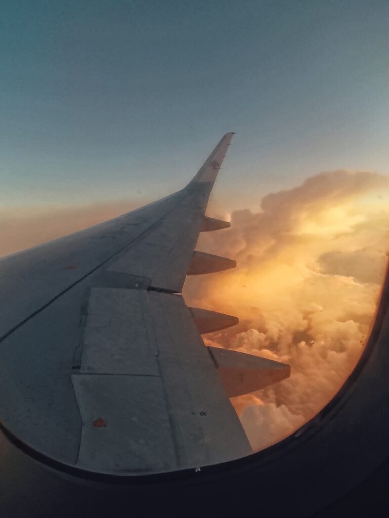 Der rechte FLugzeugflügel im Sonnenuntergang mit orangen Wolken